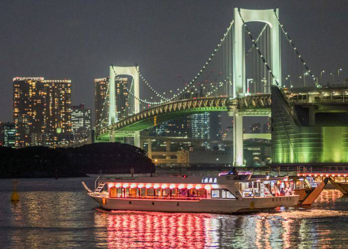 Multiple yakatabune on the Tokyo Bay, shining red with their traditional Japanese lanterns.